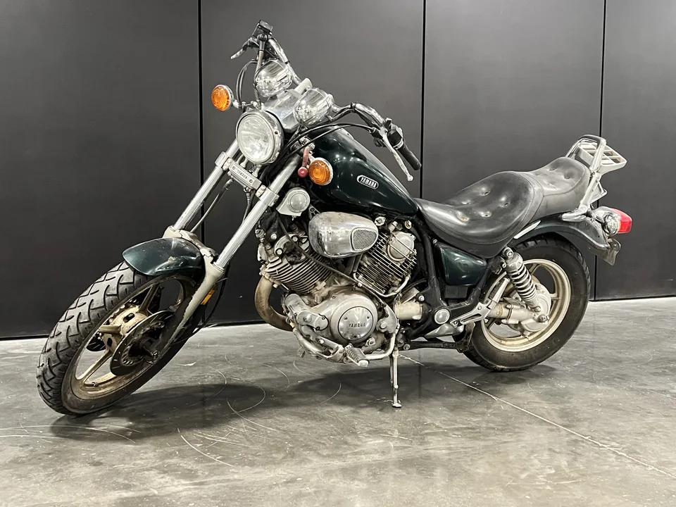 The Green Machine, a dark green Yamaha Virago 1100 cruiser, three-quarter front on the shop floor.