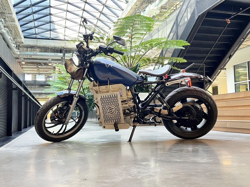 MidKnight, moto eléctrica Shandoka en chasis Yamaha XS400, de perfil, con caja de baterías de corte láser bajo el tanque azul.