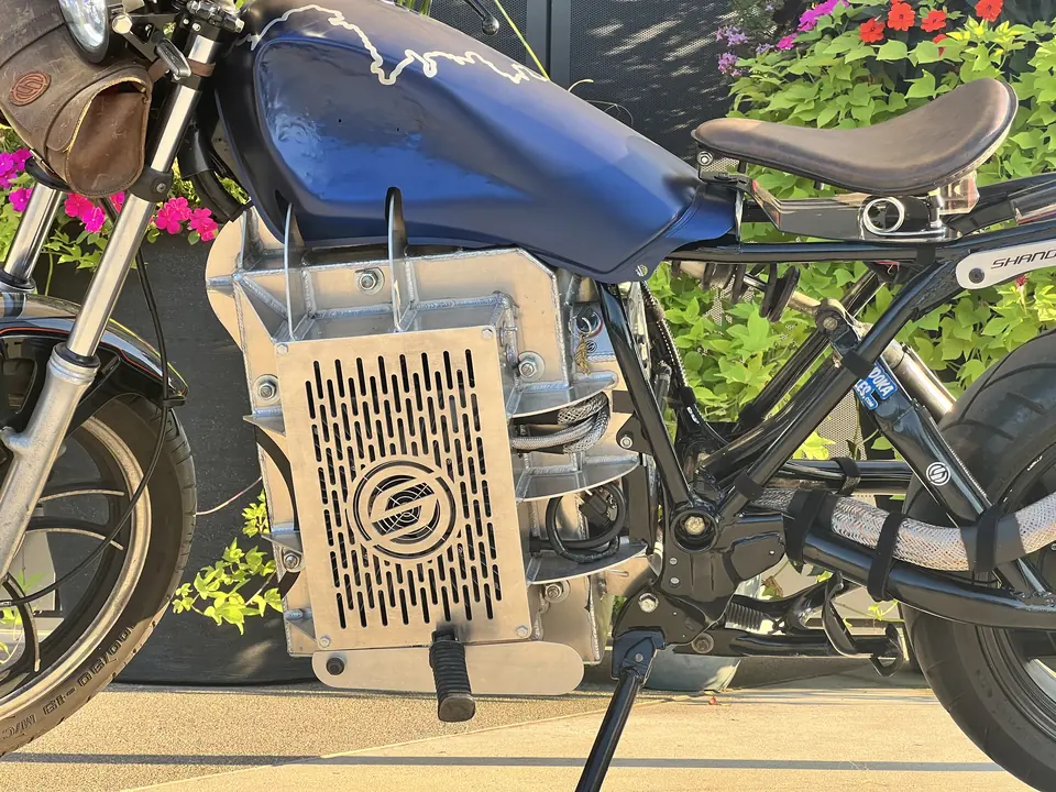 La caja de baterías de MidKnight de cerca en el chasis de la XS400, con el emblema de Shandoka cortado en el panel lateral.