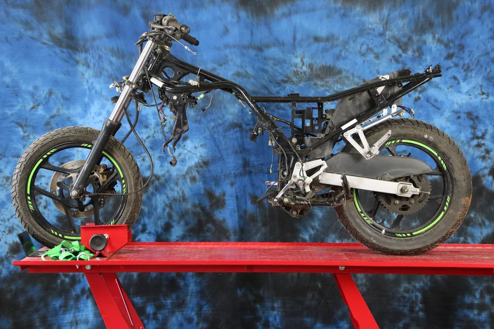 Una Kawasaki Ninja 250 en un elevador, sin motor ni carrocería, con el chasis desnudo listo para la conversión.